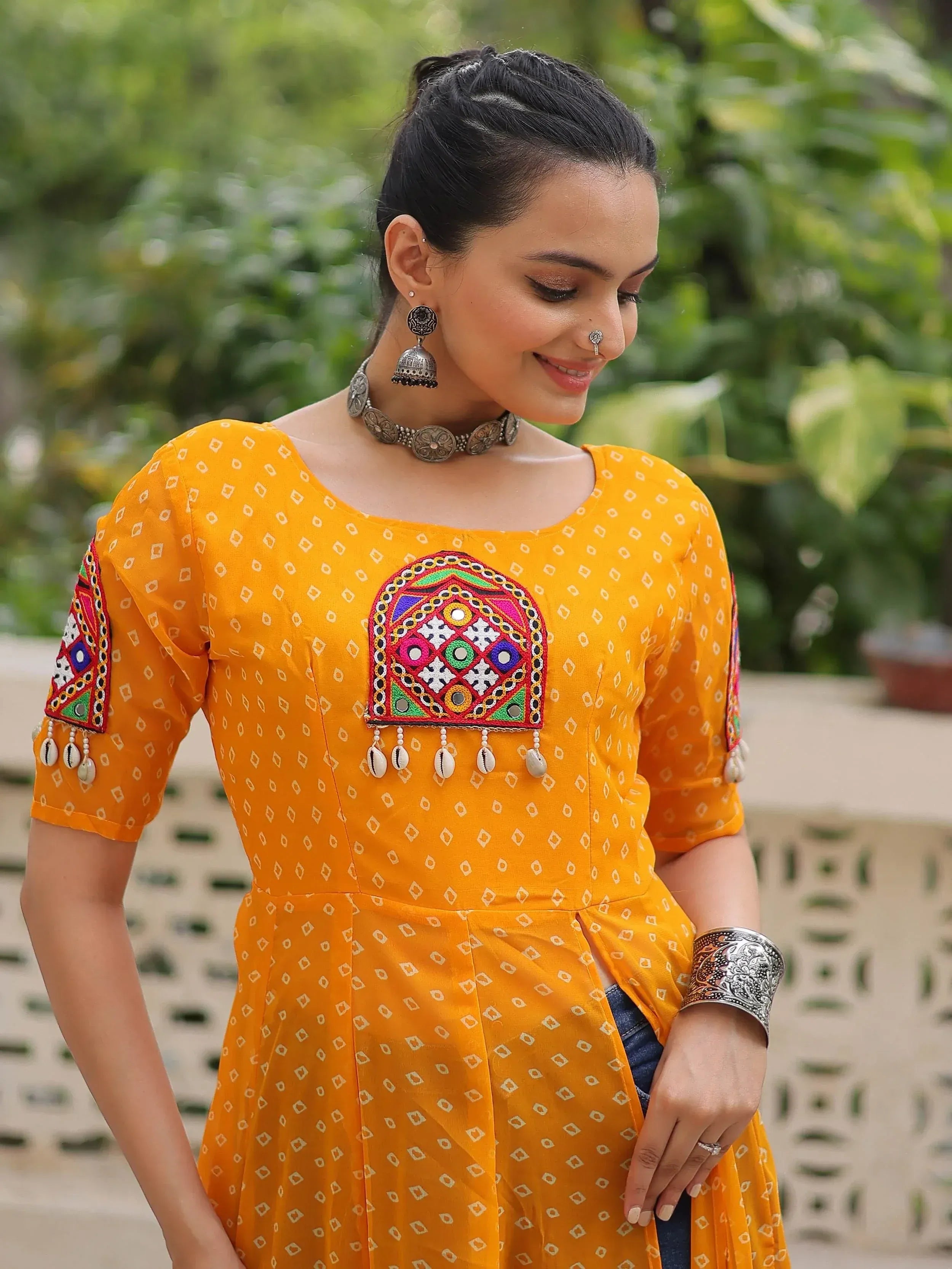 Yellow ethnic kurti with mirror work and cowrie shells, paired with silver jewelry