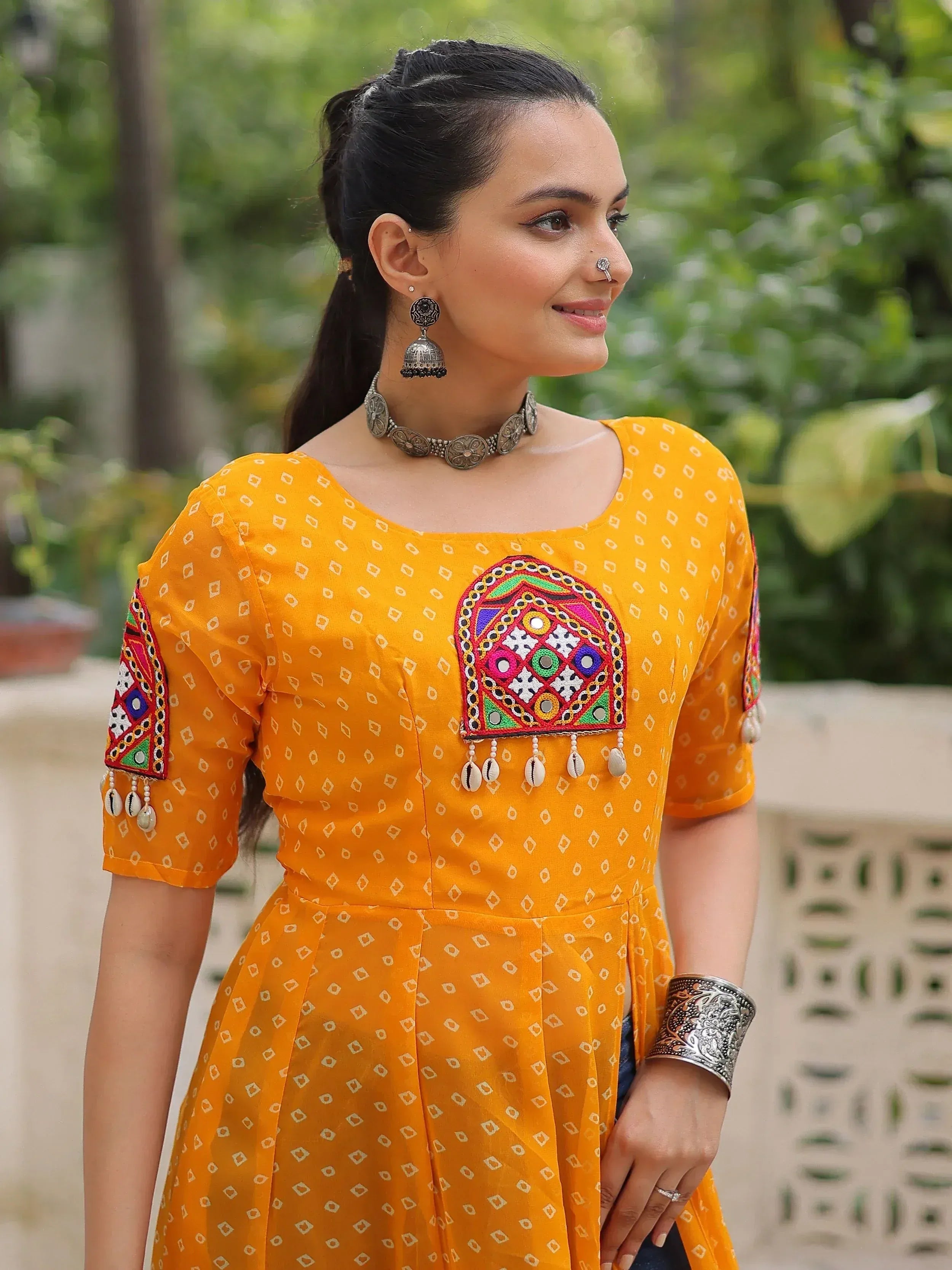 Yellow ethnic kurti with mirror work and cowrie shell embroidery, paired with silver jewelry
