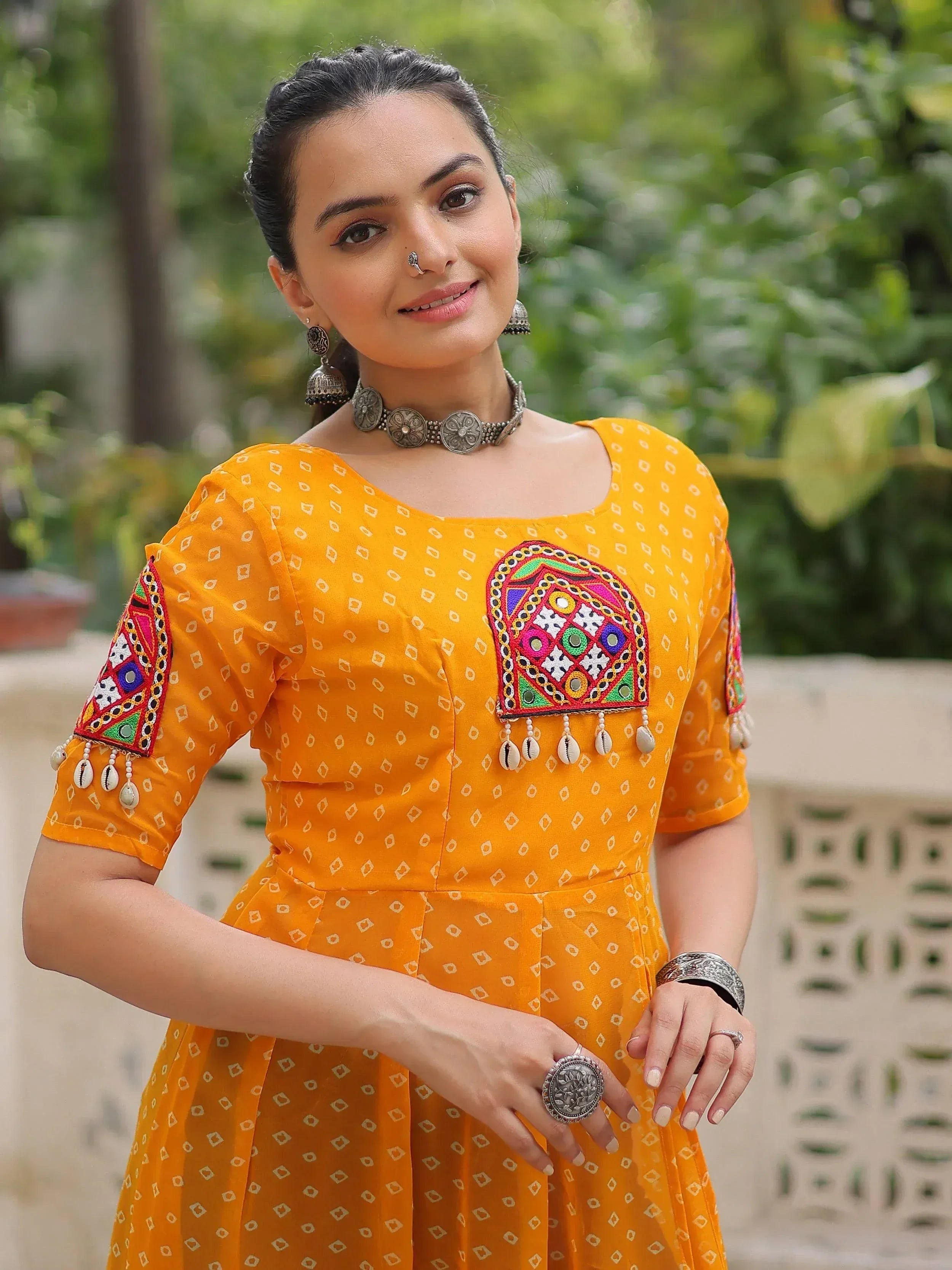 Yellow ethnic gown with mirror work and shell embroidery, styled with traditional jewelry