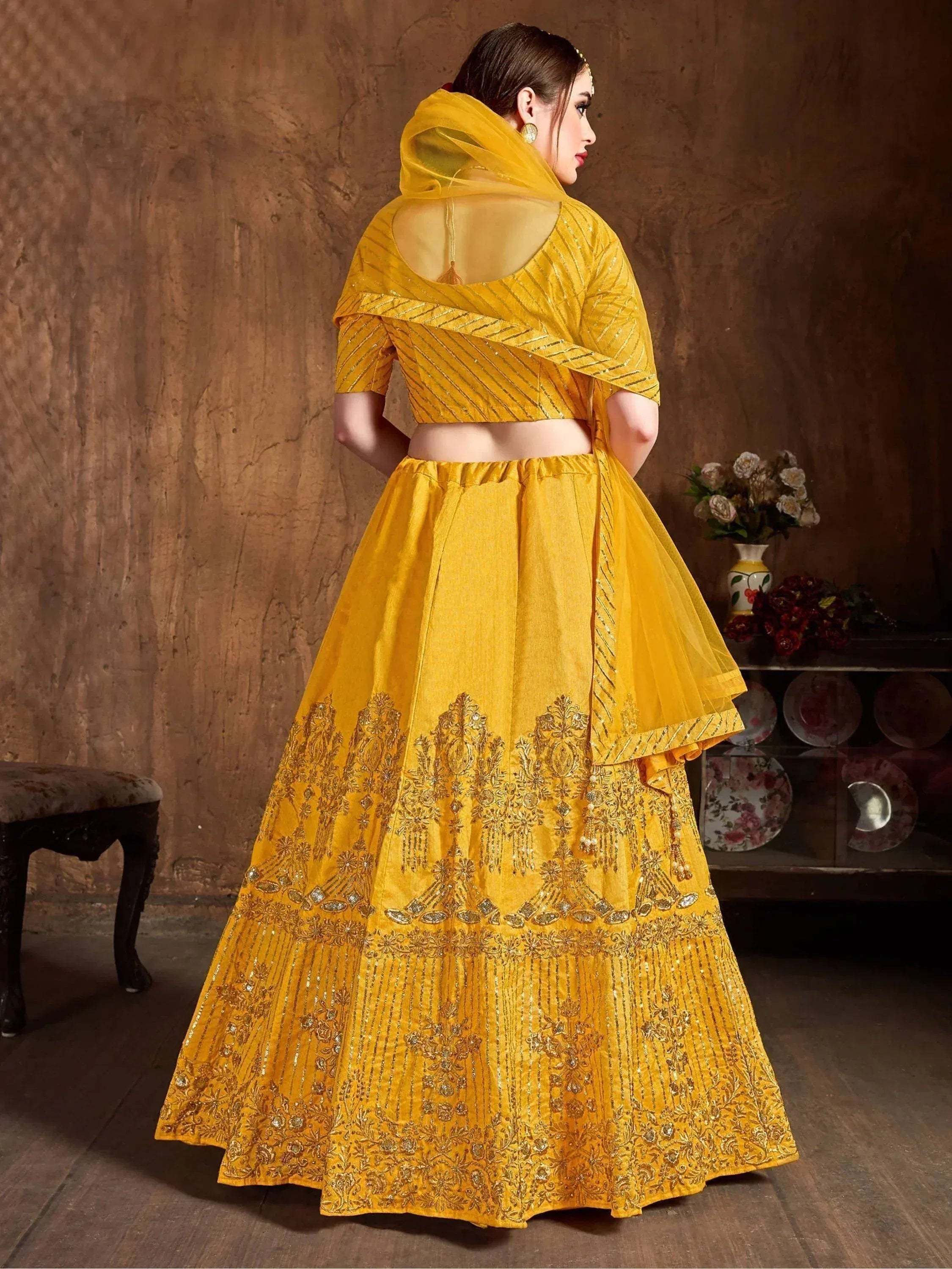 Yellow designer lehenga choli with intricate embroidery and sheer dupatta, perfect for Indian ethnic occasions.
