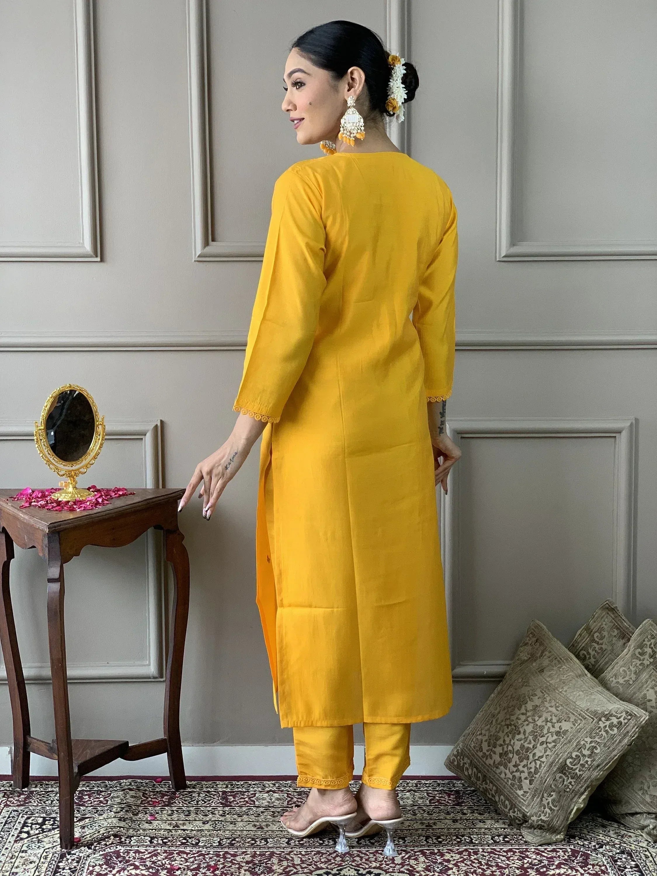 Woman in vibrant yellow ethnic kurta set with lace trim, styled with floral hair accessories and statement earrings.