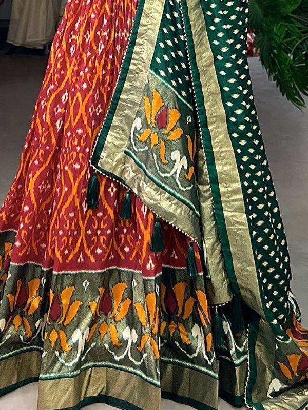 Vibrant red and green ikat lehenga choli with floral embroidery and tassels, ethnic Indian wear