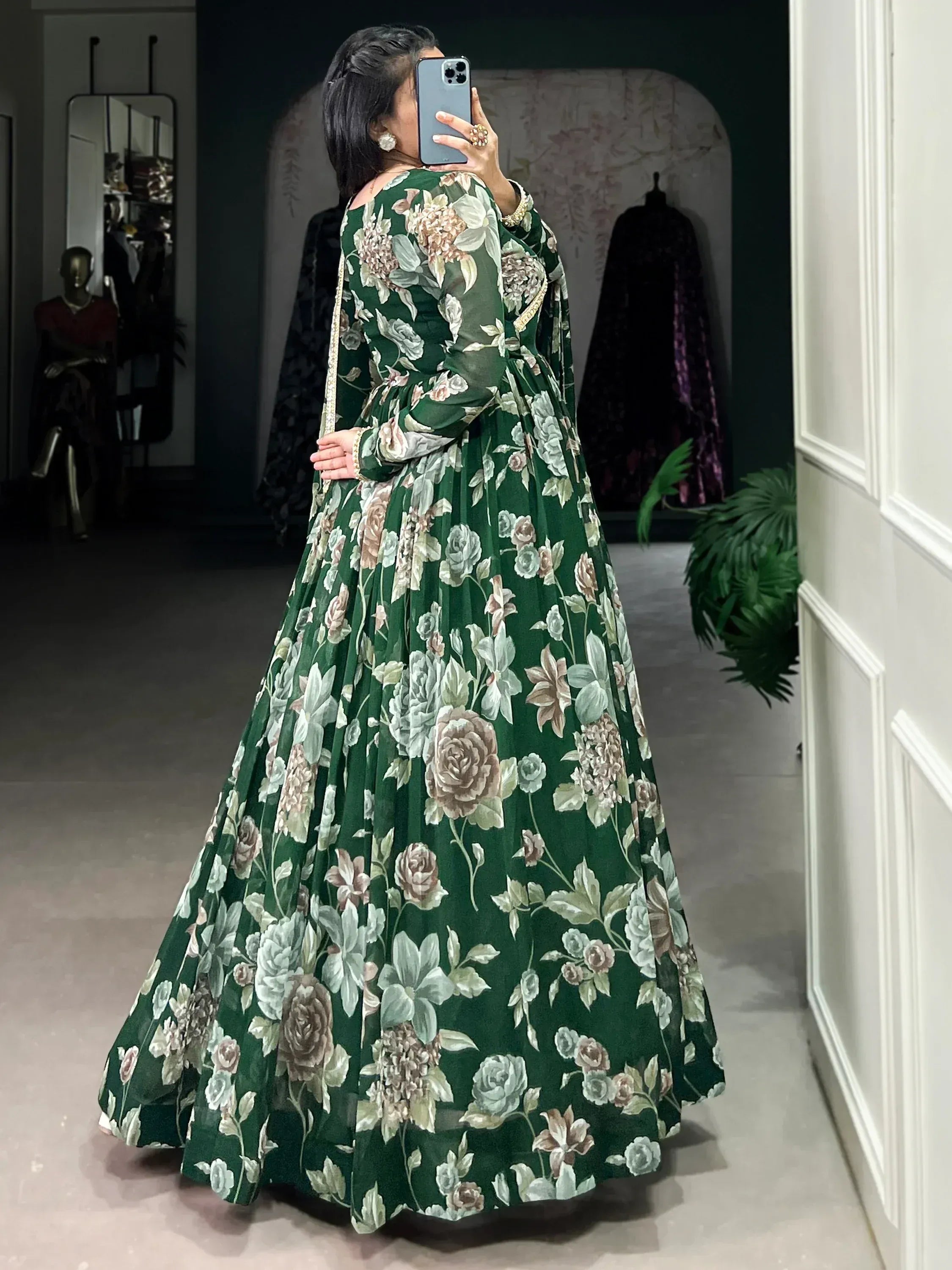 Woman in a green floral printed ethnic gown posing indoors with back facing camera
