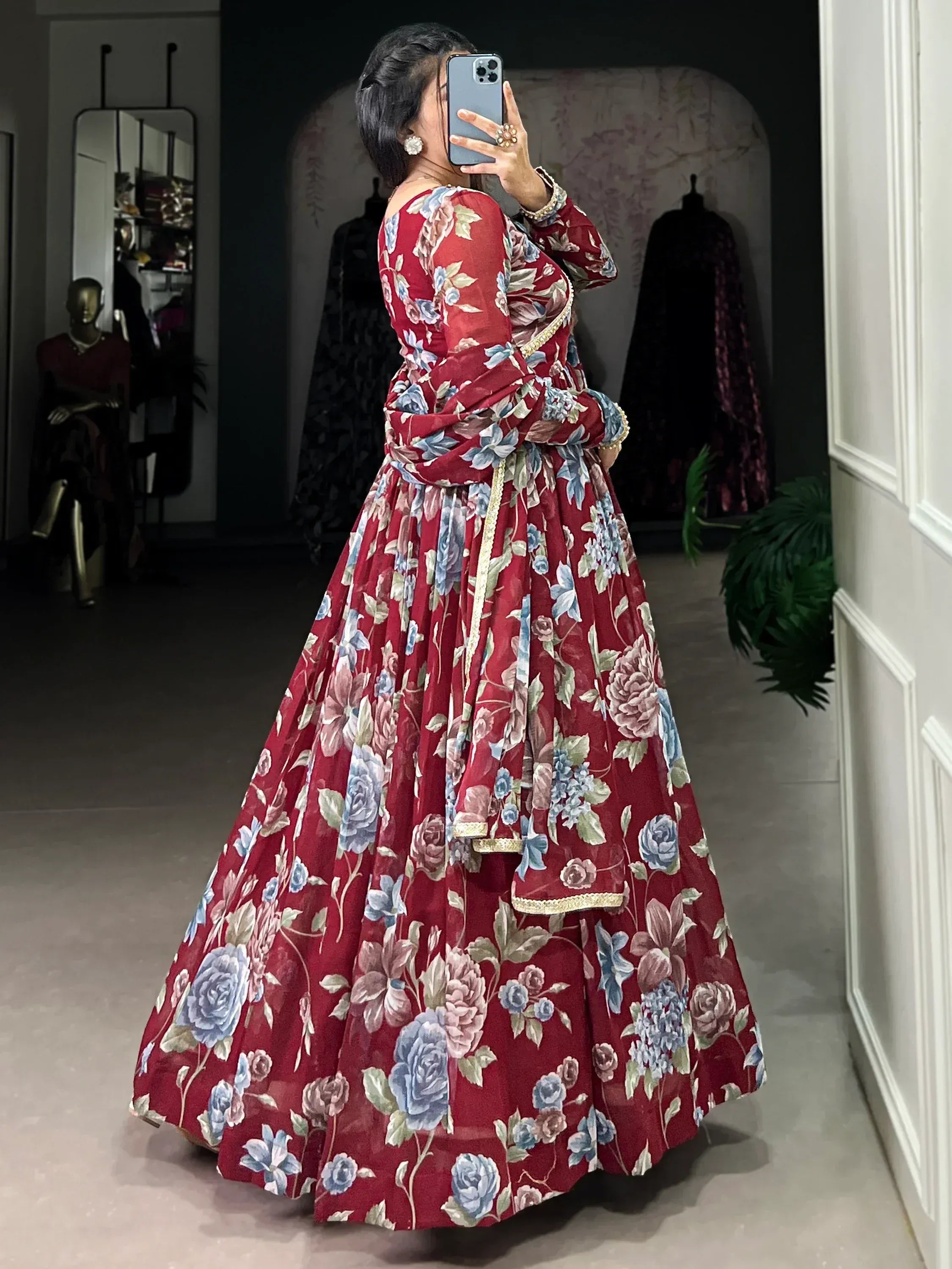 Red floral lehenga choli with blue and pink blooms, gold trim, mirror selfie in boutique
