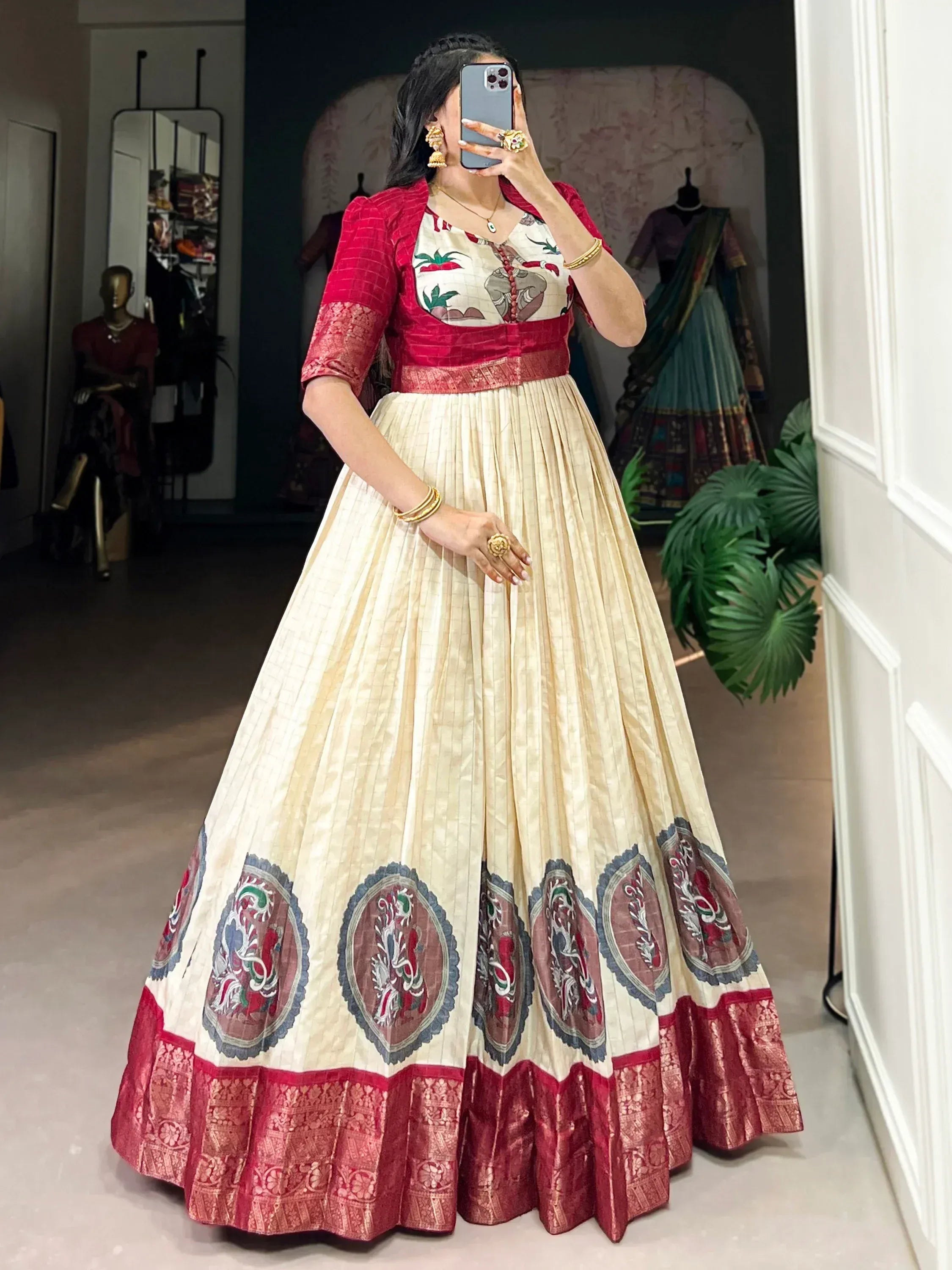 Cream and red embroidered lehenga choli with floral motifs and gold jewelry, perfect for Indian ethnic wear.