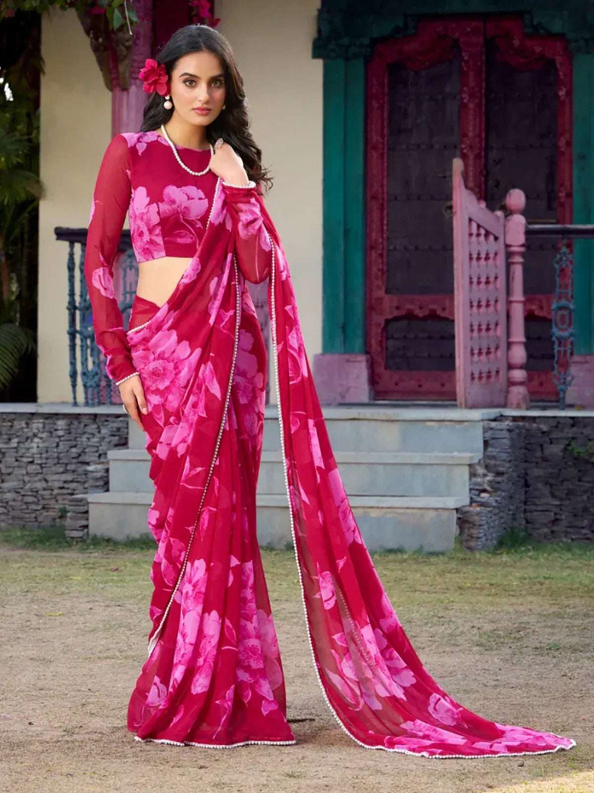 Pink floral saree with sheer sleeves and pearl trim, styled with traditional Indian accessories