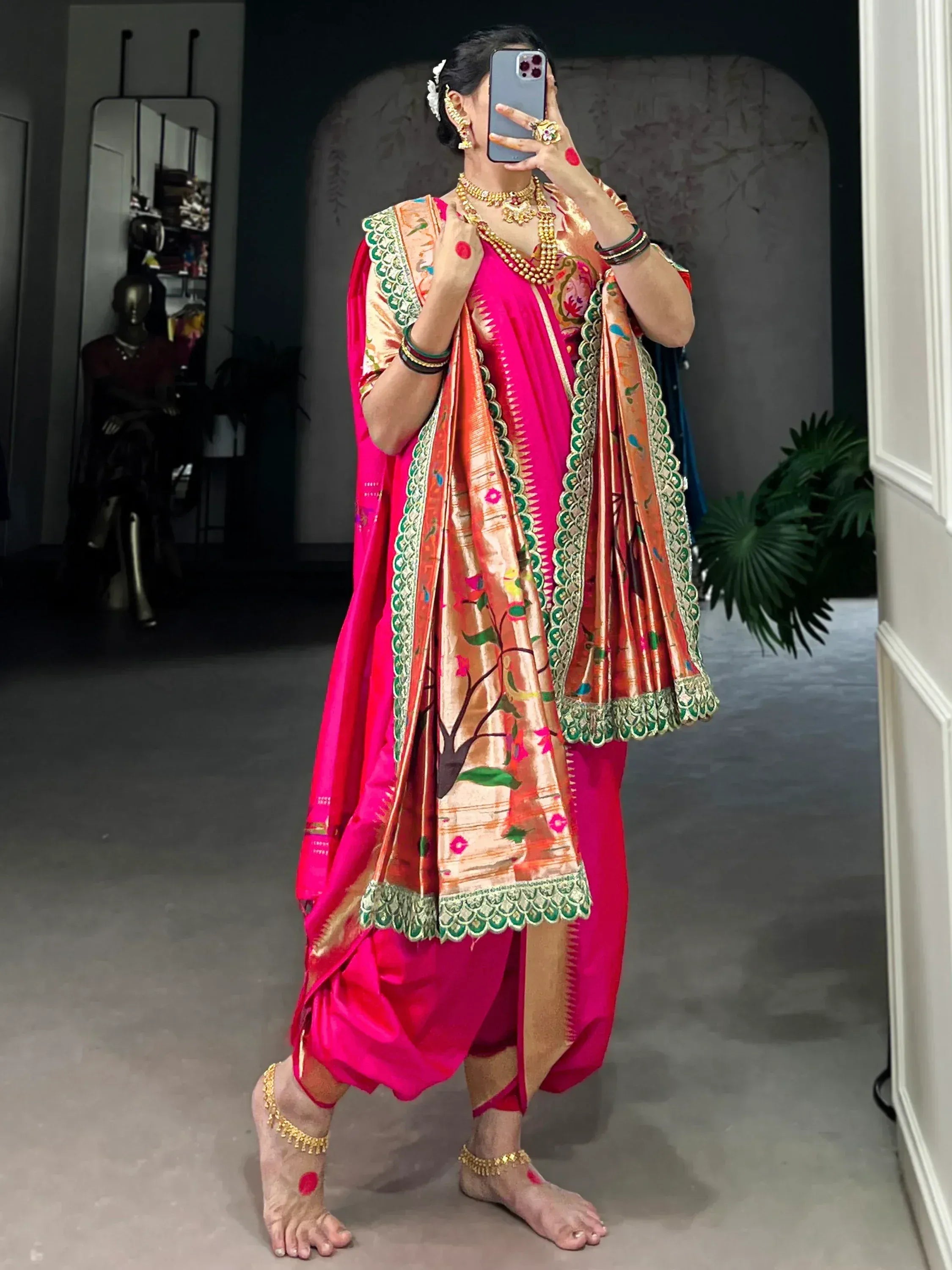 Vibrant pink ethnic saree with floral embroidery and gold jewelry, perfect for festive occasions.