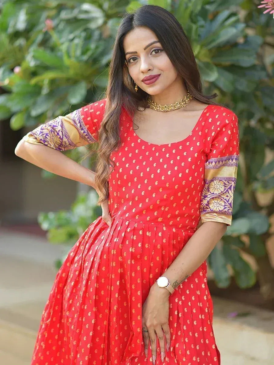 Woman in red printed ethnic gown with gold motifs and purple embroidered sleeves, outdoors