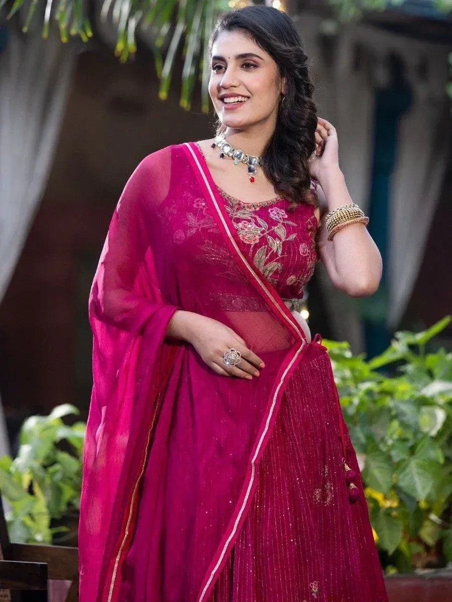 Woman in vibrant pink embroidered lehenga choli with sheer dupatta, perfect for Indian ethnic occasions