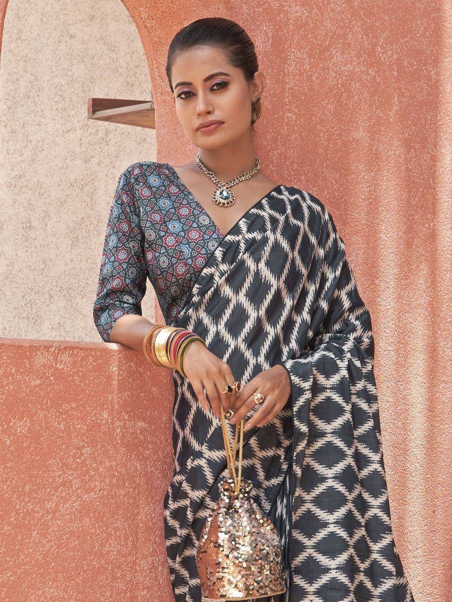 Woman in black and white geometric print saree with colorful blouse, gold jewelry, and sequin bag