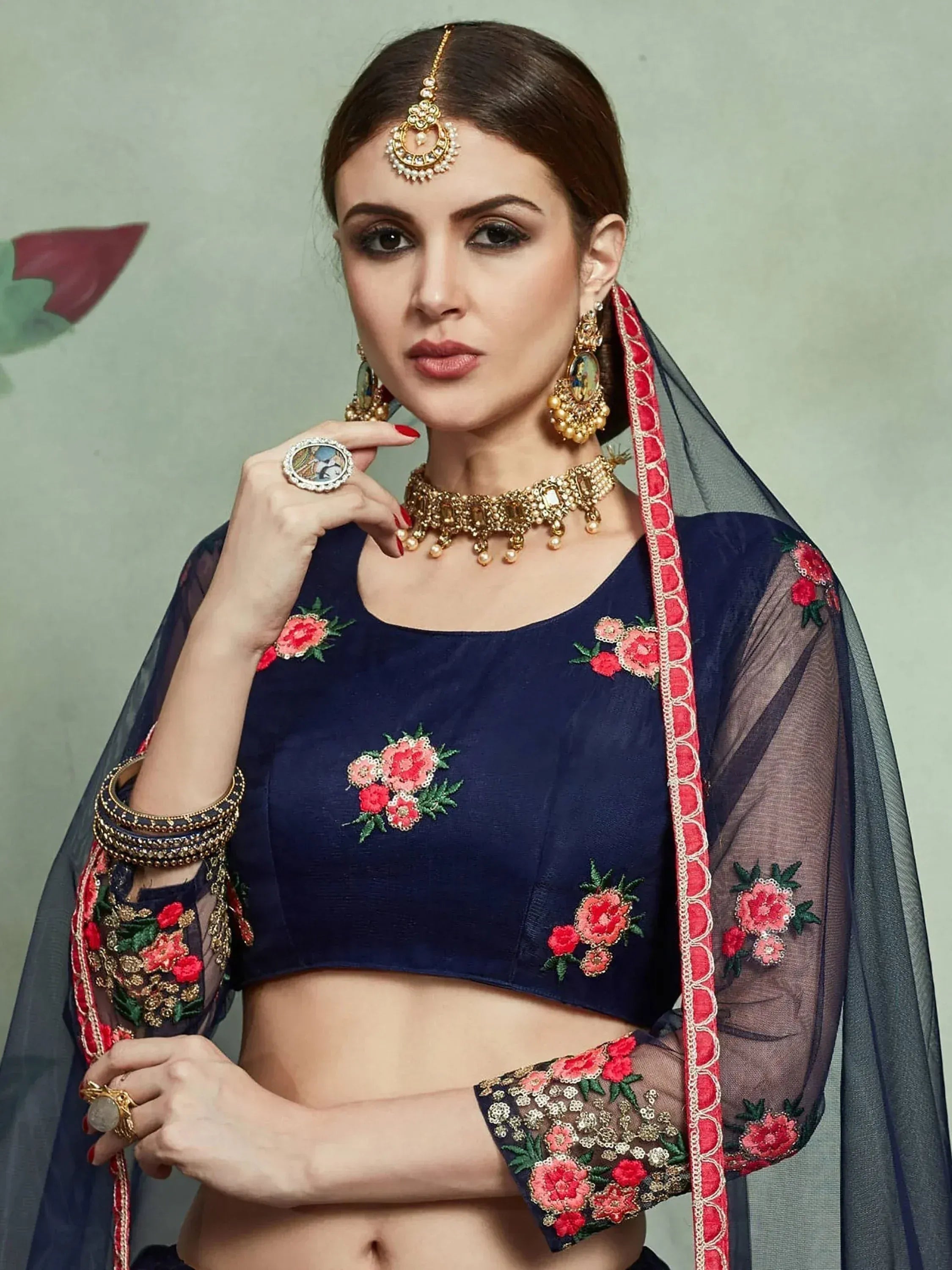 Navy blue embroidered lehenga choli with floral detailing and sheer dupatta, paired with traditional Indian jewelry