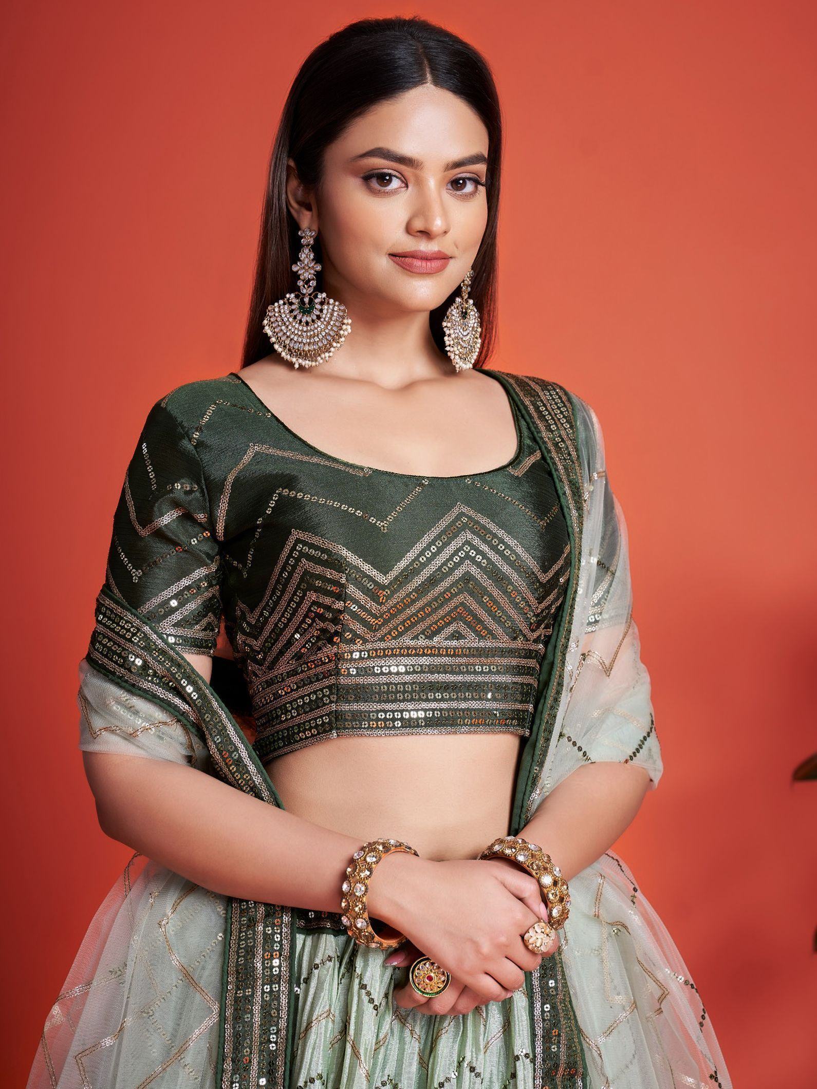Green sequin lehenga choli with chevron embroidery, sheer dupatta, and statement jewelry for Indian ethnic wear