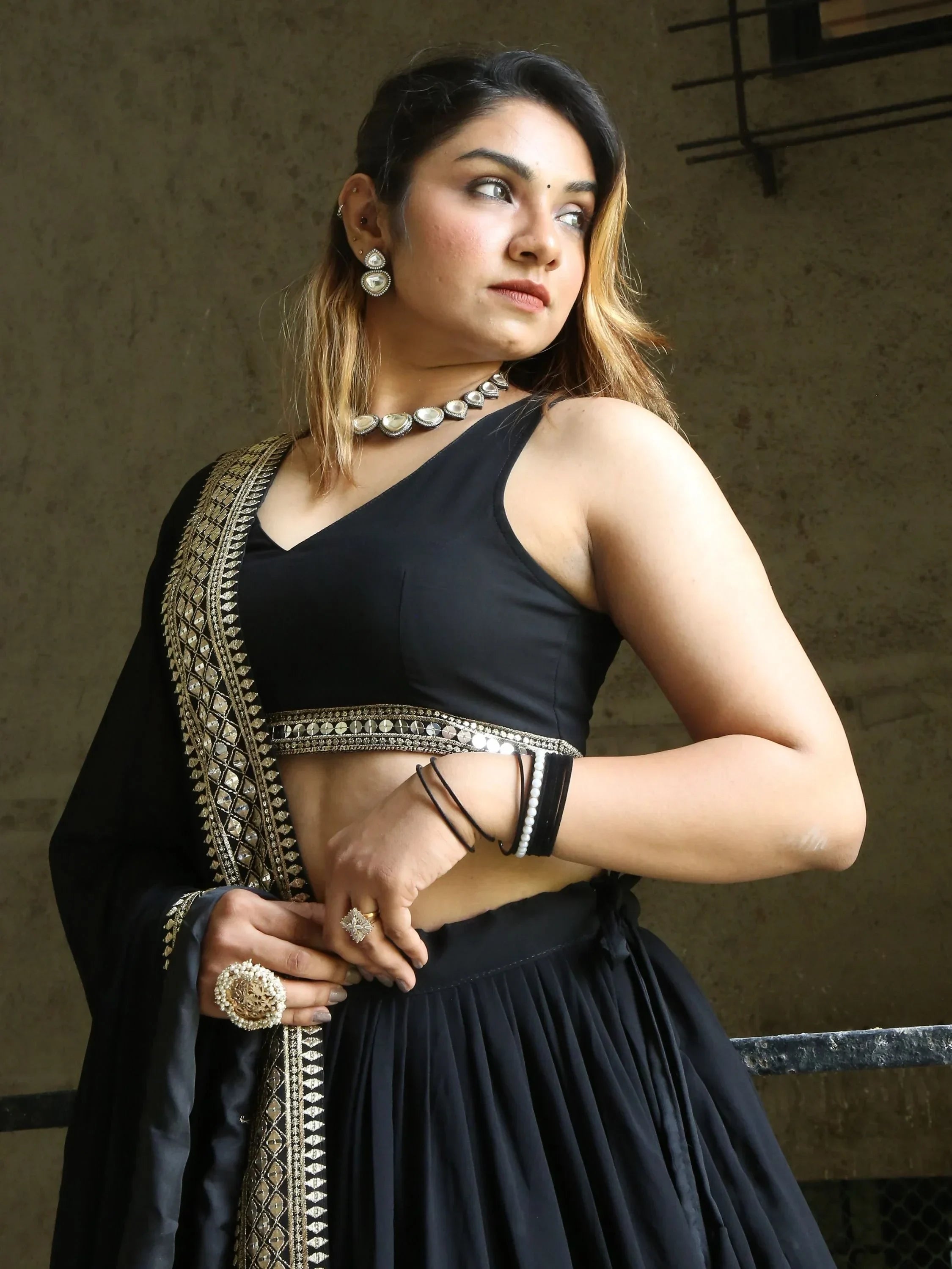 Black designer lehenga choli with gold embroidery and mirror work, paired with statement jewelry