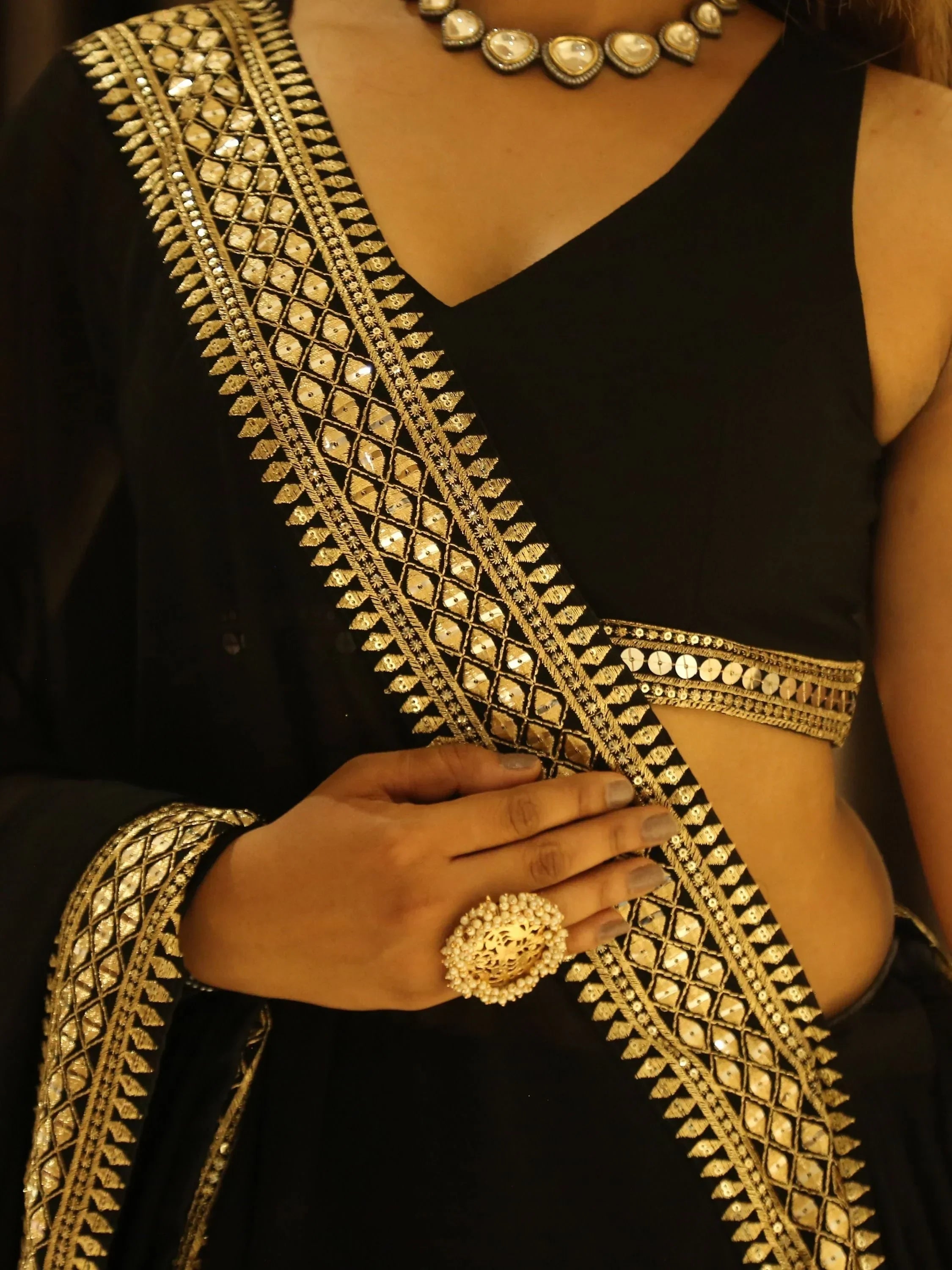 Black ethnic gown with gold mirror work, paired with statement jewelry for festive occasions.