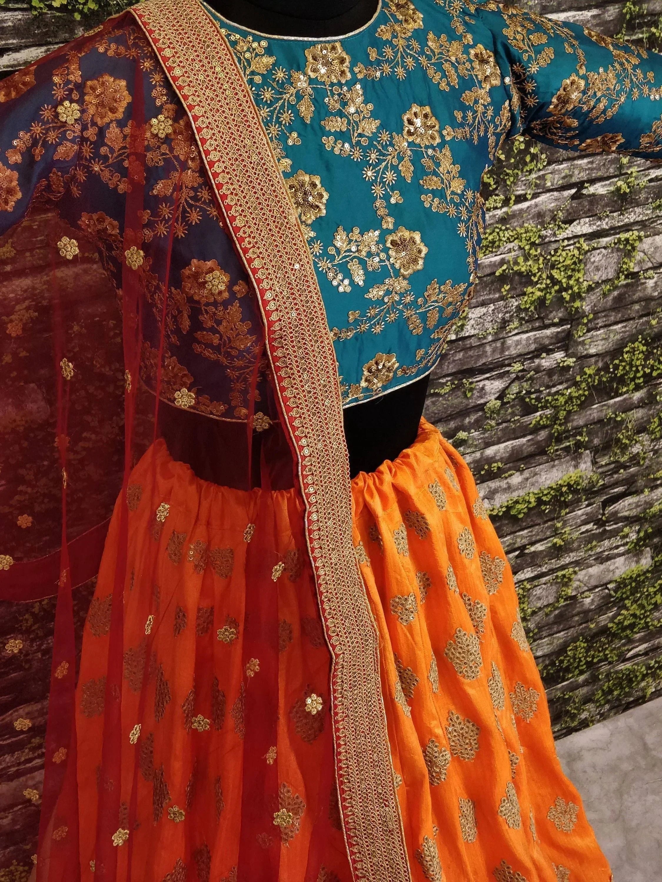 Teal and orange embroidered lehenga choli with gold floral work and matching dupatta, ideal for Indian ethnic occasions.