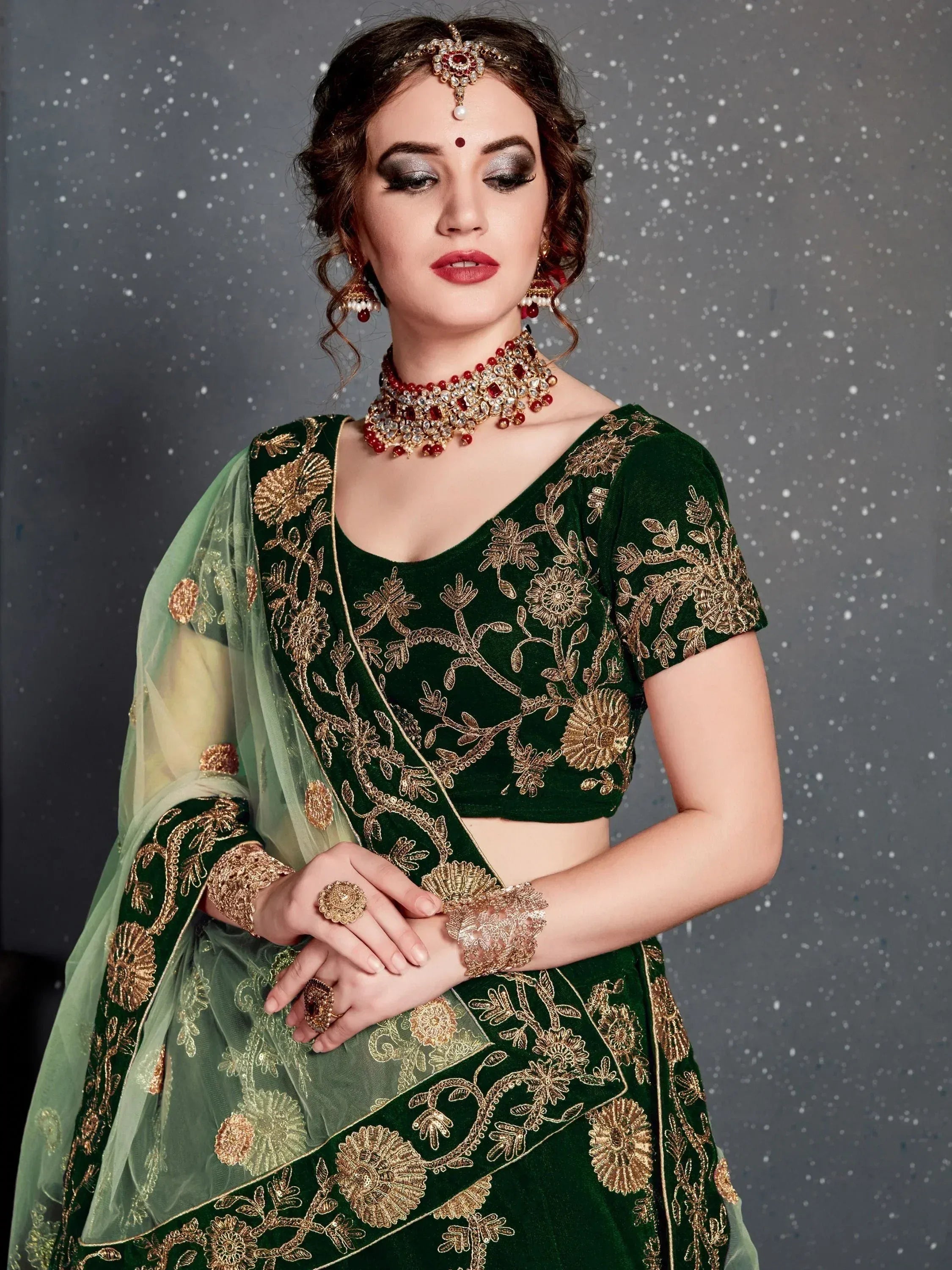 Emerald green velvet lehenga choli with gold floral embroidery, perfect for Indian weddings and festive occasions.