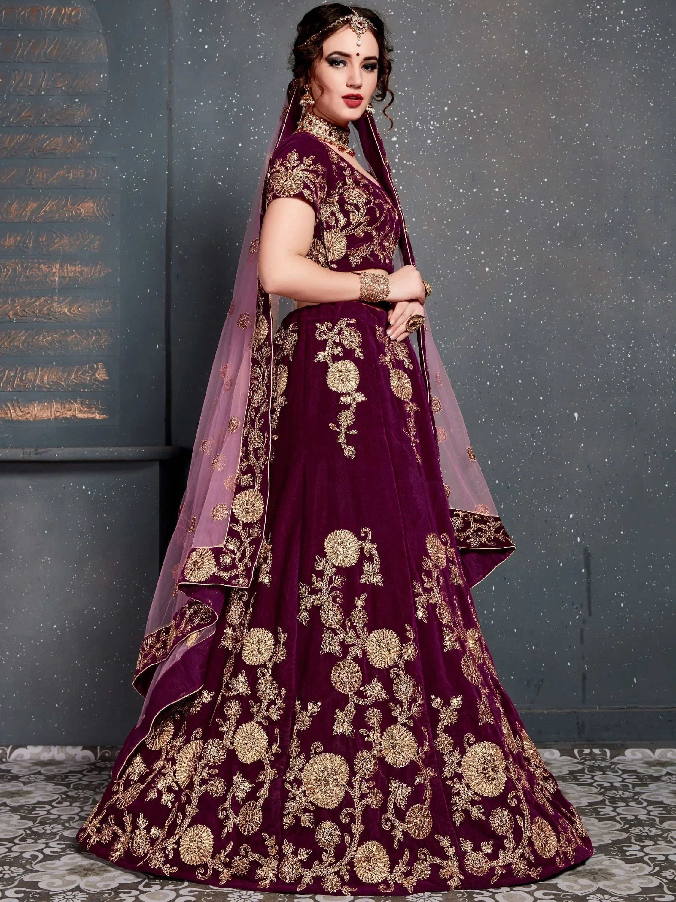 Elegant maroon velvet lehenga choli with gold floral embroidery, perfect for Indian weddings and festive occasions.