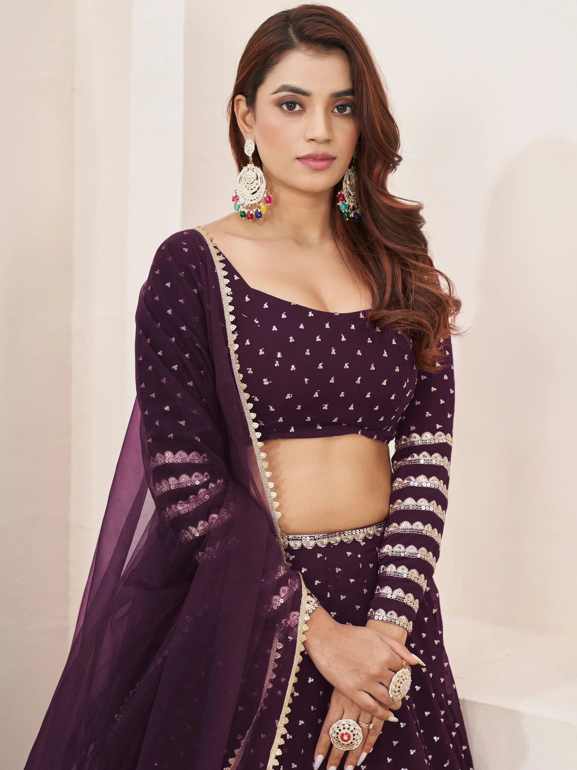 Purple ethnic lehenga choli with gold embroidery and sheer dupatta, styled with colorful jhumka earrings