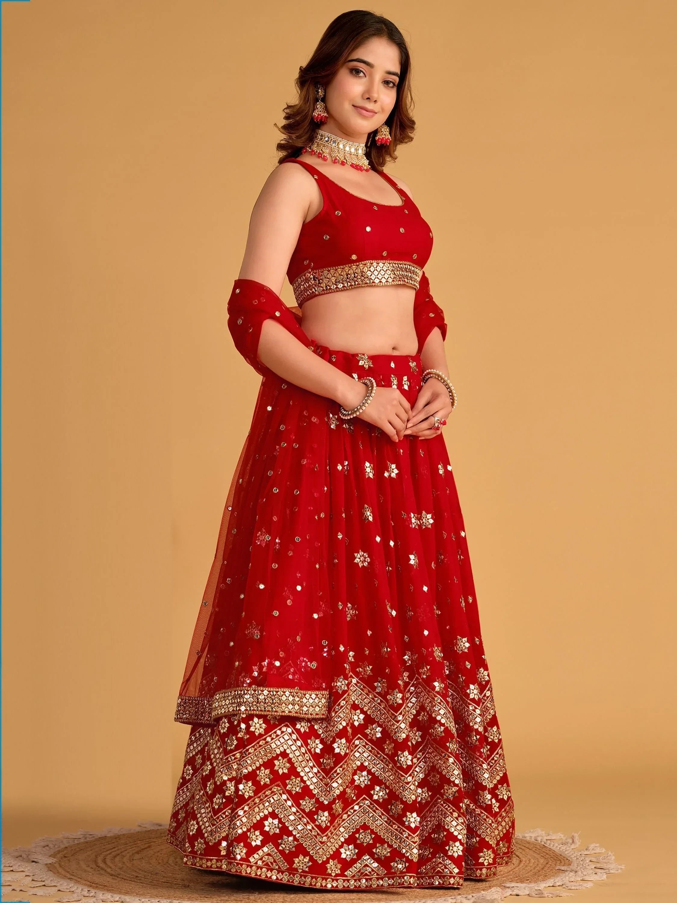 Red designer lehenga choli with gold mirror work, perfect for Indian weddings and festive occasions.