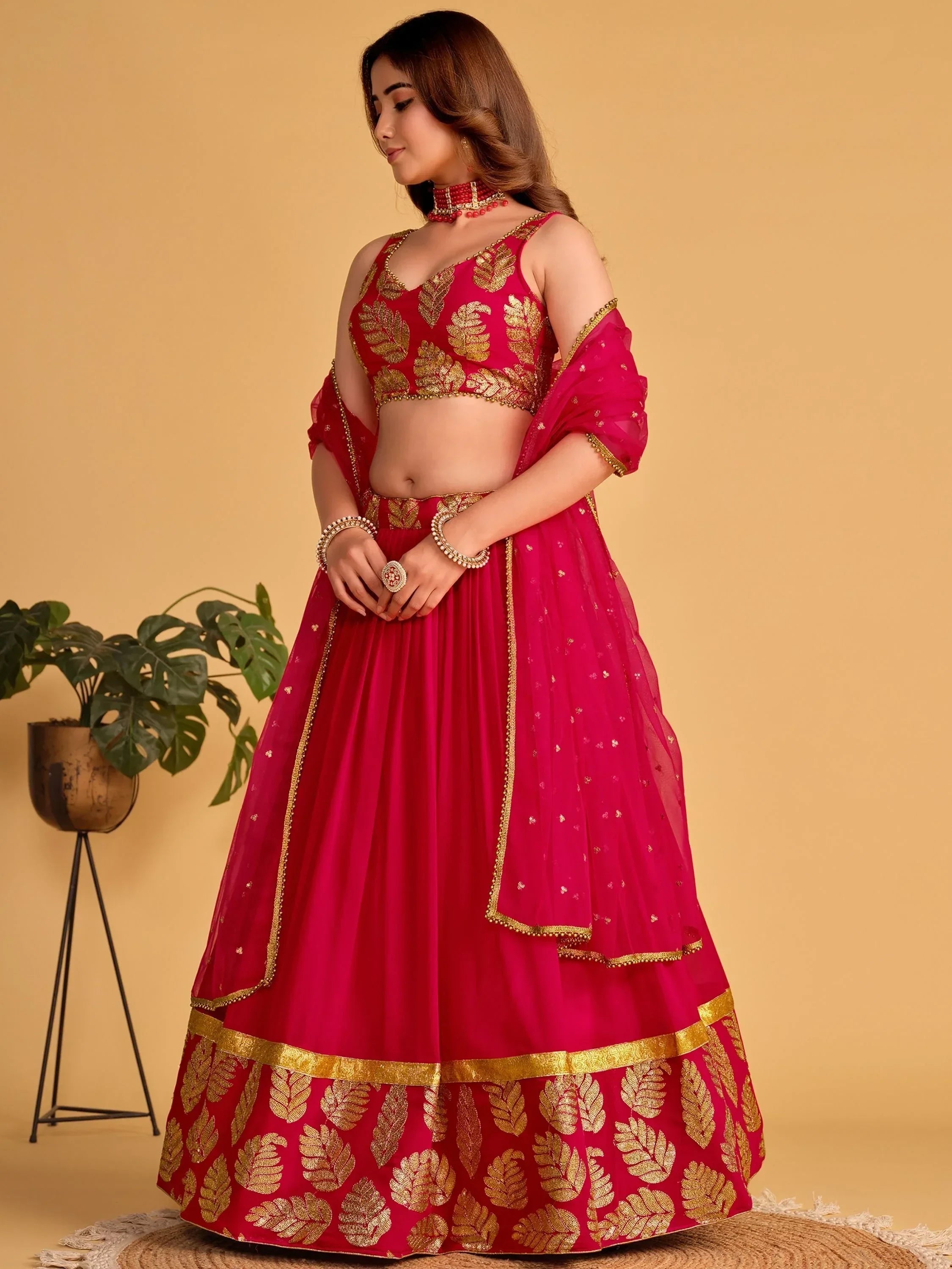 Red and gold embroidered lehenga choli with leaf motifs, perfect for Indian ethnic occasions