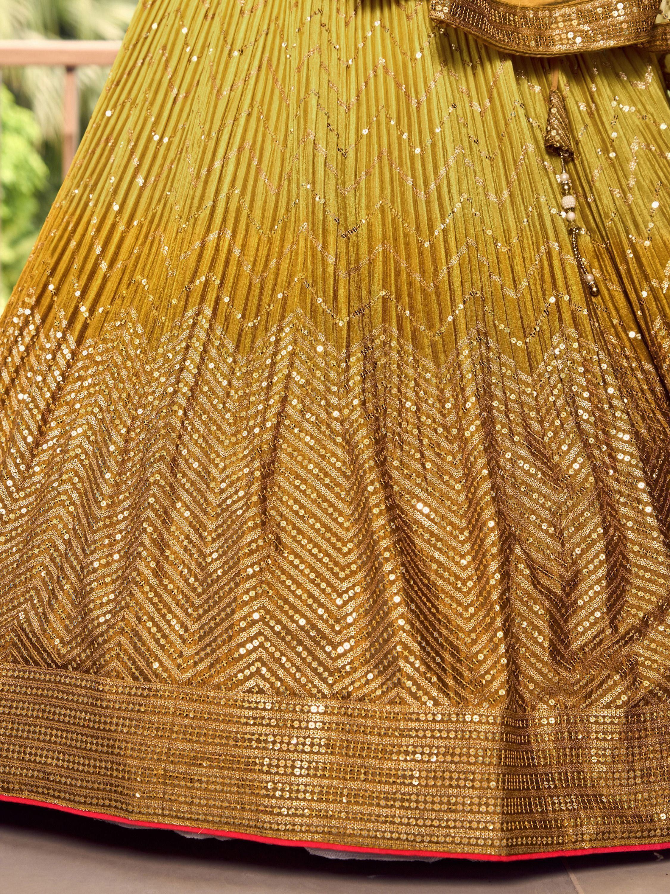 Golden pleated lehenga with sequin chevron patterns and tassel detail, ideal for Indian ethnic wear.