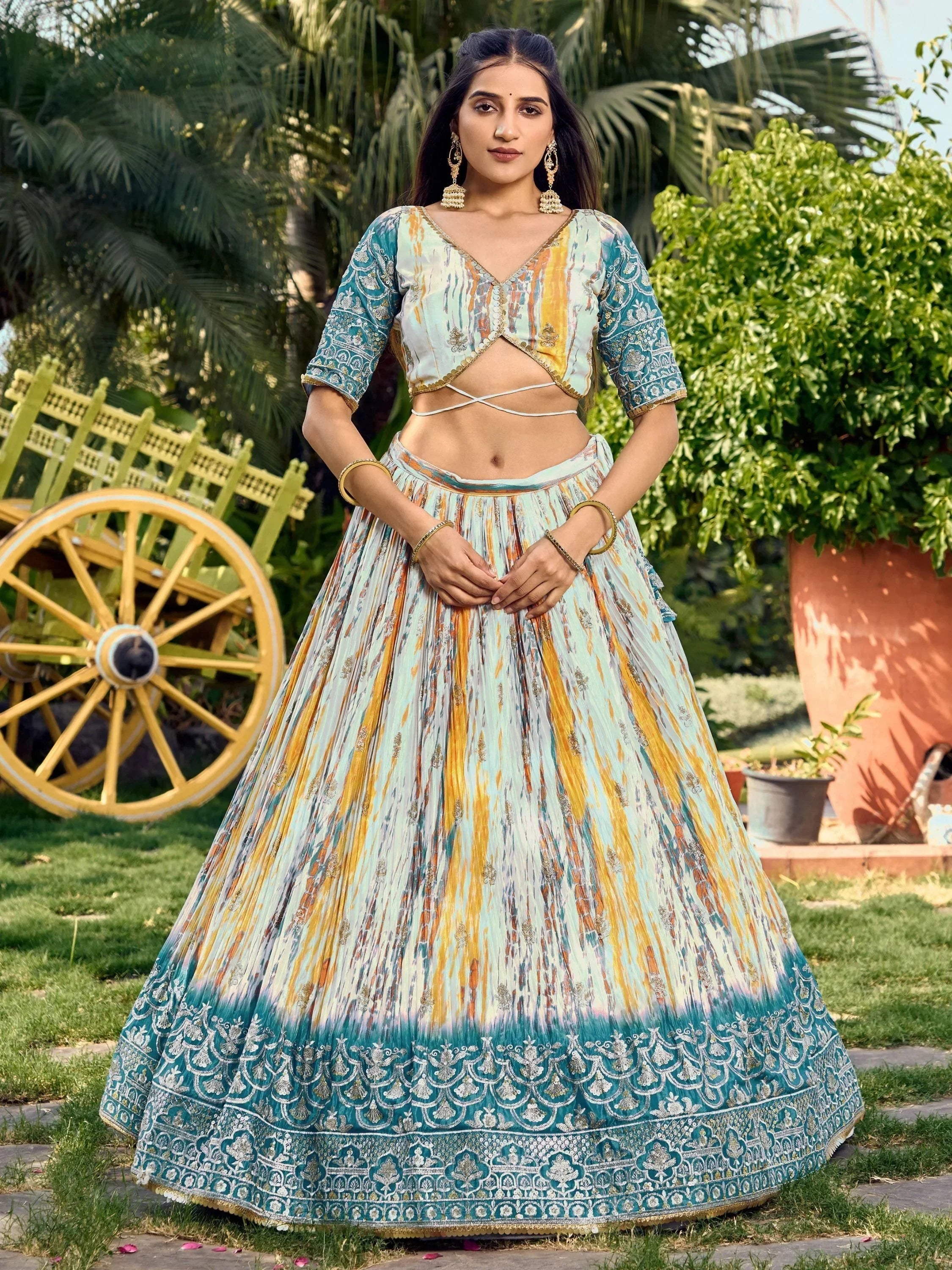 Woman in designer lehenga choli with ikat print, gold embroidery, and pleated skirt, perfect for Indian ethnic occasions