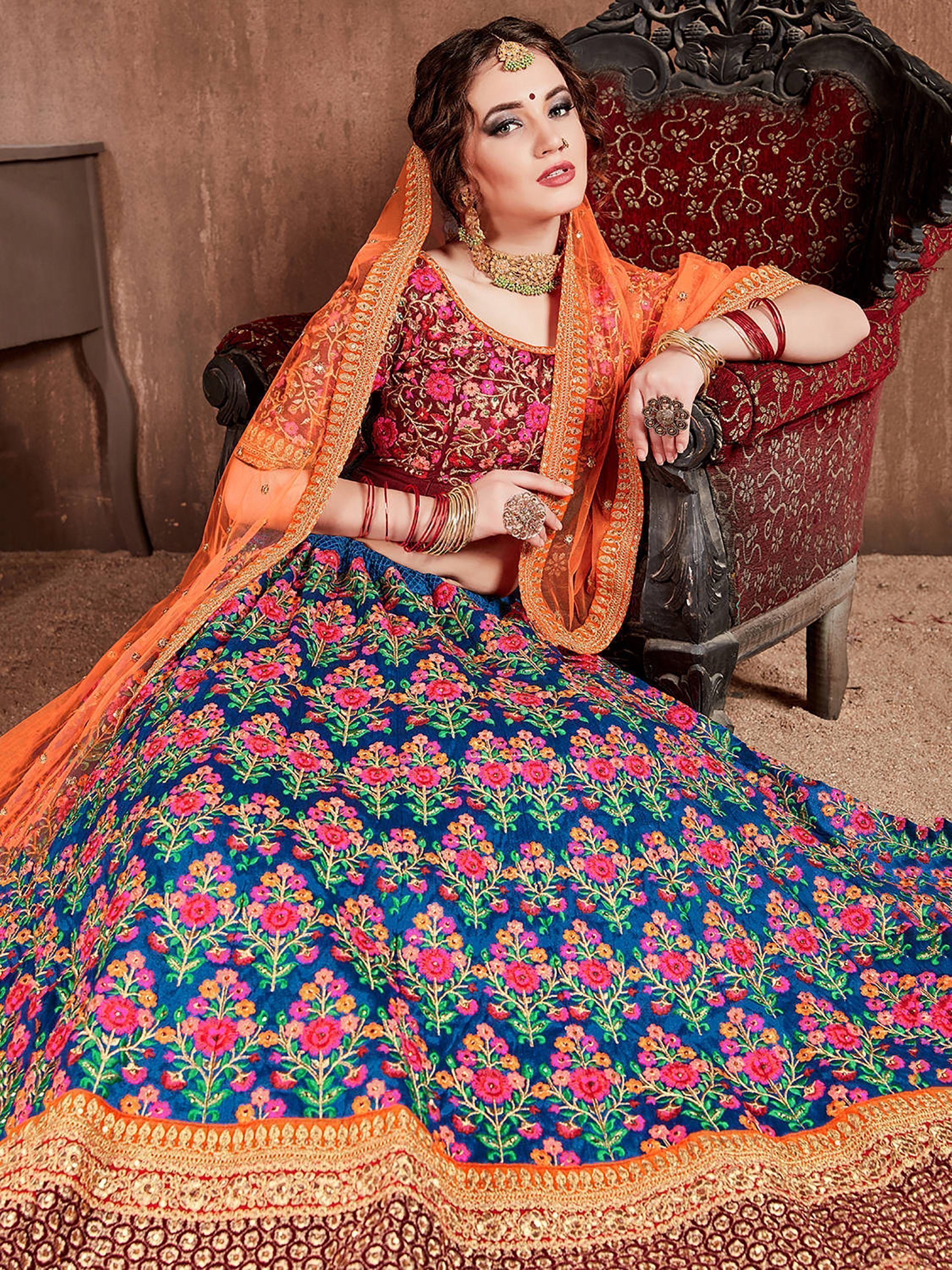 Woman in vibrant floral lehenga choli with orange dupatta, traditional Indian ethnic wear for weddings and festivals